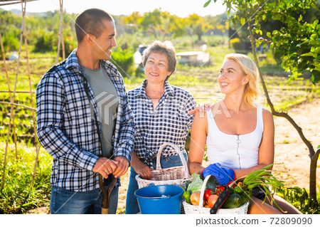 Mom with adults children rejoices at the harvest of vegetables Mom with adults children rejoices at the harvest of vegetables 72809090
