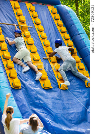 Males climbing on inflatable slide 72809122