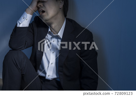 A businessman sitting on the floor in a dark room A businessman sitting on the floor in a dark room 72809123