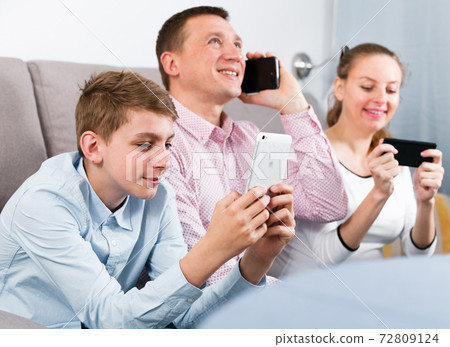 Parents and son using phones 72809124