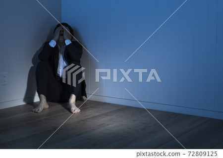 一位商人坐在黑暗的房間裡的地板上 一位商人坐在黑暗的房間裡的地板上 72809125