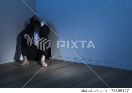 A businessman sitting on the floor in a dark room A businessman sitting on the floor in a dark room 72809127