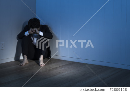 一位商人坐在黑暗的房間裡的地板上 一位商人坐在黑暗的房間裡的地板上 72809128