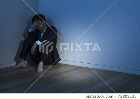 一位商人坐在黑暗的房間裡的地板上 一位商人坐在黑暗的房間裡的地板上 72809133