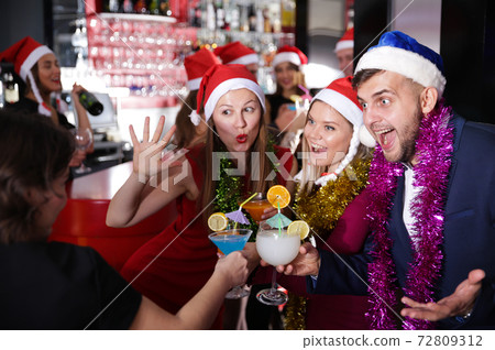 Man and two women in Santa hats celebrating at nightclub 72809312