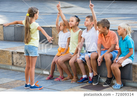 Cheerful boys and girls playing charades Cheerful boys and girls playing charades 72809314
