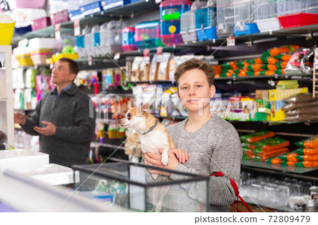 Portrait of happy teen boy with his little dog visiting pet supplies shop 72809479
