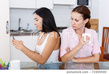 Mother looking into smartphone Mother looking into smartphone 72809480