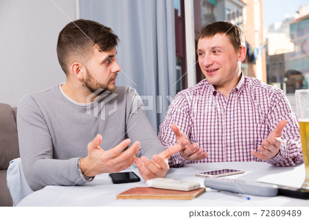 Men enjoying conversation at home table Men enjoying conversation at home table 72809489