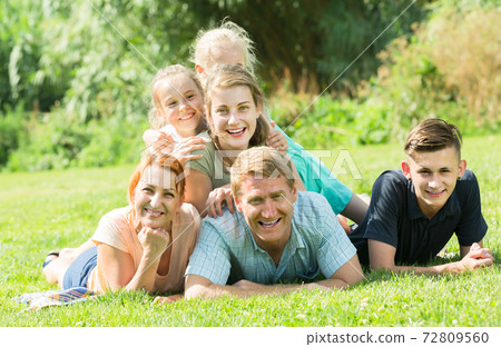 Adult man and woman with kids lying in park 72809560