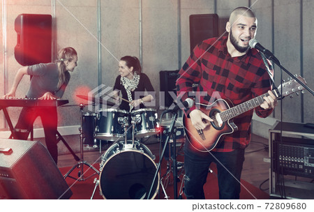 Bearded guy soloist playing guitar in studio 72809680