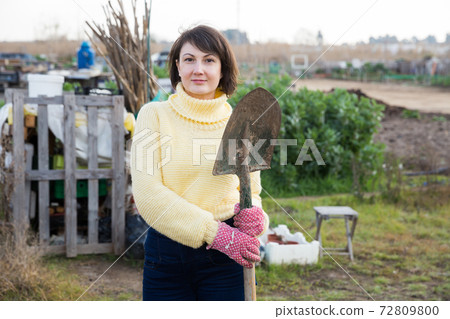 Female gardener standing with spade 72809800