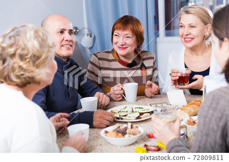 Mature women and their friend are drinking tea and talking Mature women and their friend are drinking tea and talking 72809811