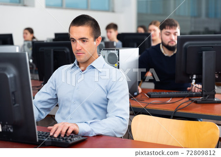 Group of people of different ages learning to use computers in classroom Group of people of different ages learning to use computers in classroom 72809812