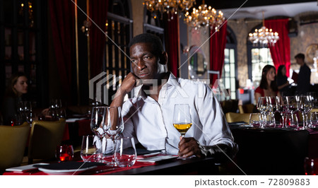 Afro man drinking wine in restaurant Afro man drinking wine in restaurant 72809883