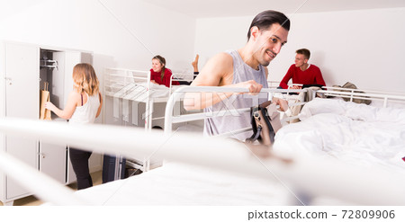 Man getting up to top bunk of bed in hostel Man getting up to top bunk of bed in hostel 72809906