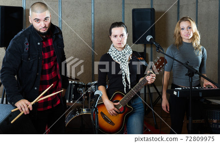 expressive group of rock musicians posing with instruments expressive group of rock musicians posing with instruments 72809975