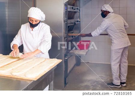Female baker prepares delicious dough coca bread at bakery Female baker prepares delicious dough coca bread at bakery 72810165