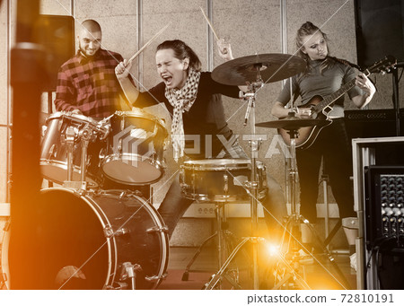 Rehearsal of music group with female drummer 72810191