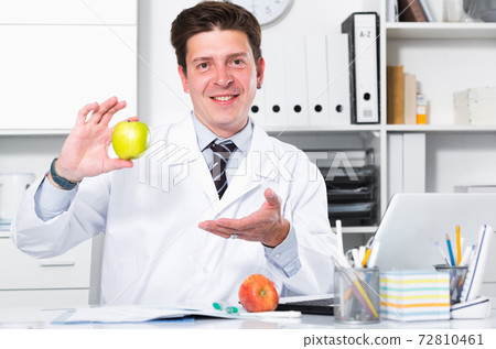 Dentist in medical Center sitting at the table 72810461