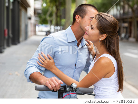 Couple hugging during riding together kick scooter in city center Couple hugging during riding together kick scooter in city center 72810528