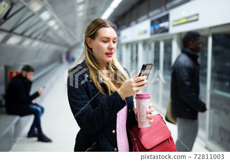 Woman using phone at underground station Woman using phone at underground station 72811003
