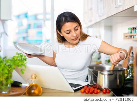 Nice latino woman planning to cook, looking for recipe on internet Nice latino woman planning to cook, looking for recipe on internet 72811005