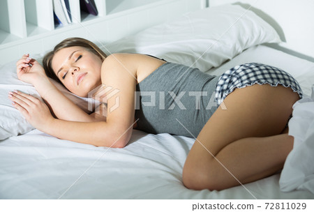 Young female in pygamas is sleeping on bed 72811029