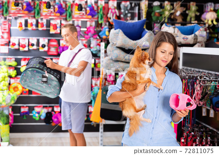 Happy young woman with dog in pet store during shopping with man Happy young woman with dog in pet store during shopping with man 72811075