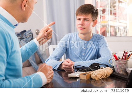 Teenager listening to reprimanding father Teenager listening to reprimanding father 72811079