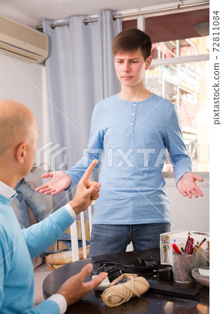 Serious father lecturing his son Serious father lecturing his son 72811084
