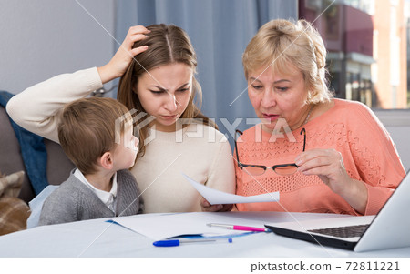 Adult female with her mother are having problems with filling documents near laptop Adult female with her mother are having problems with filling documents near laptop 72811221