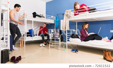Young men and women friendly interacting while staying in modern comfy hostel Young men and women friendly interacting while staying in modern comfy hostel 72811522