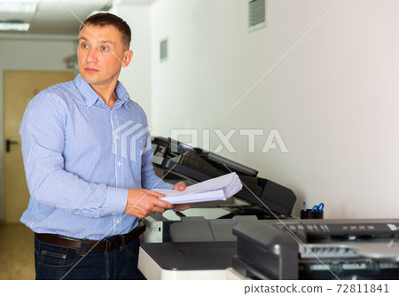 Office worker puts a stack of paper in the printer Office worker puts a stack of paper in the printer 72811841