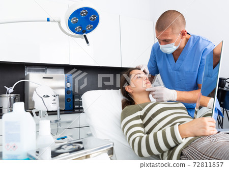 Cosmetician explaining hardware facial procedure to female client Cosmetician explaining hardware facial procedure to female client 72811857