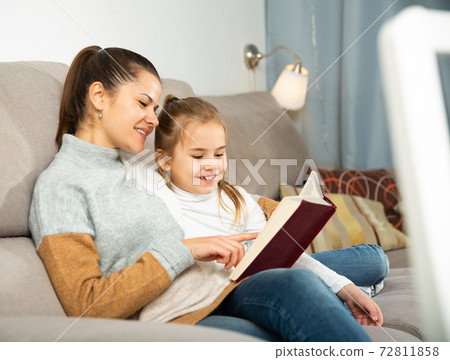 Mother reads an interesting book for her small daughter 72811858