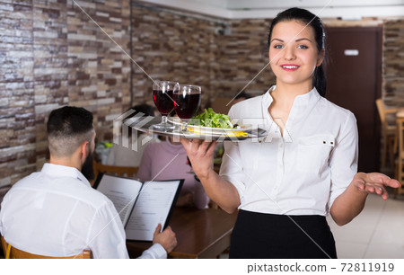 Smiling waitress greeting customers at table Smiling waitress greeting customers at table 72811919