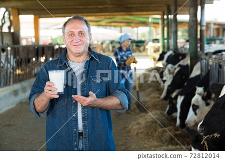 Male farm owner with milk on dairy farm 72812014
