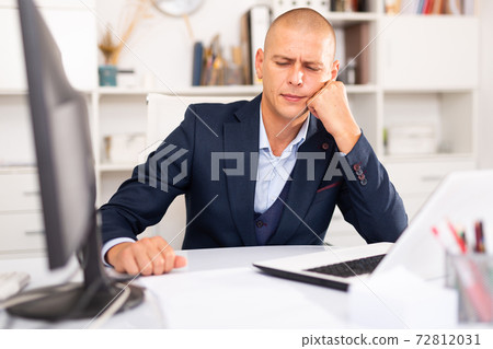 Tired businessman working with documents in office Tired businessman working with documents in office 72812031