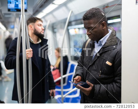African American man using mobile phone in metro car 72812053