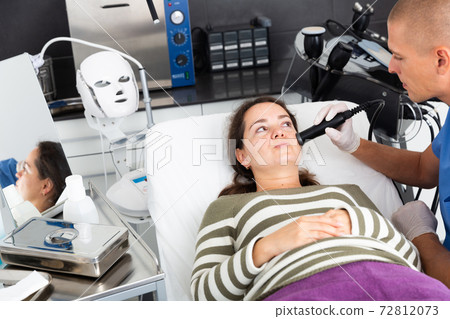 Woman during face ultrasound lifting procedure 72812073