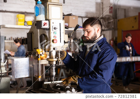Portrait of man working with drilling machine on metal plate Portrait of man working with drilling machine on metal plate 72812381