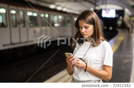 Female using mobile phone on station Female using mobile phone on station 72812382