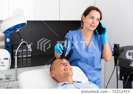 Man receiving face ultrasound lifting procedure 72812453