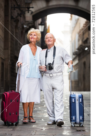 Mature travelers strolling with luggage 72812565