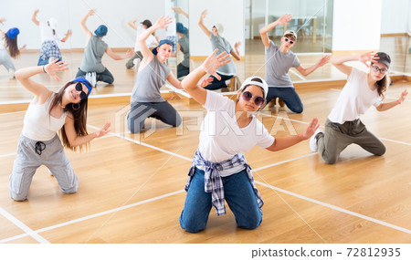 Happy smiling teenagers practicing vigorous hip hop movements in class 72812935