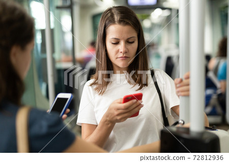 Woman with phone in streetcar 72812936