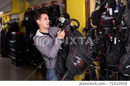 Active male is trying new diving vest in the shop 72812939
