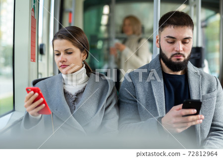 Girl and guy with phones in city bus 72812964
