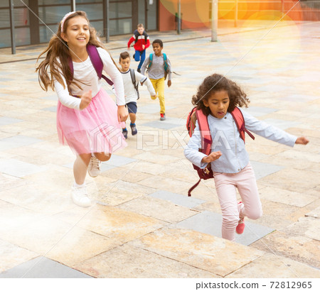 Team of positive schoolchildren running in race in the street Team of positive schoolchildren running in race in the street 72812965